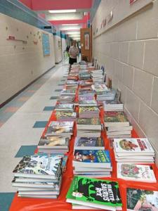 Books on display for selection by students at Long Neck Elementary during their spring Book Fair. Rotarian Cathy Cardaneo stands in rear, ready to assist.